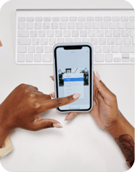 Hands holding a smartphone above a laptop keyboard